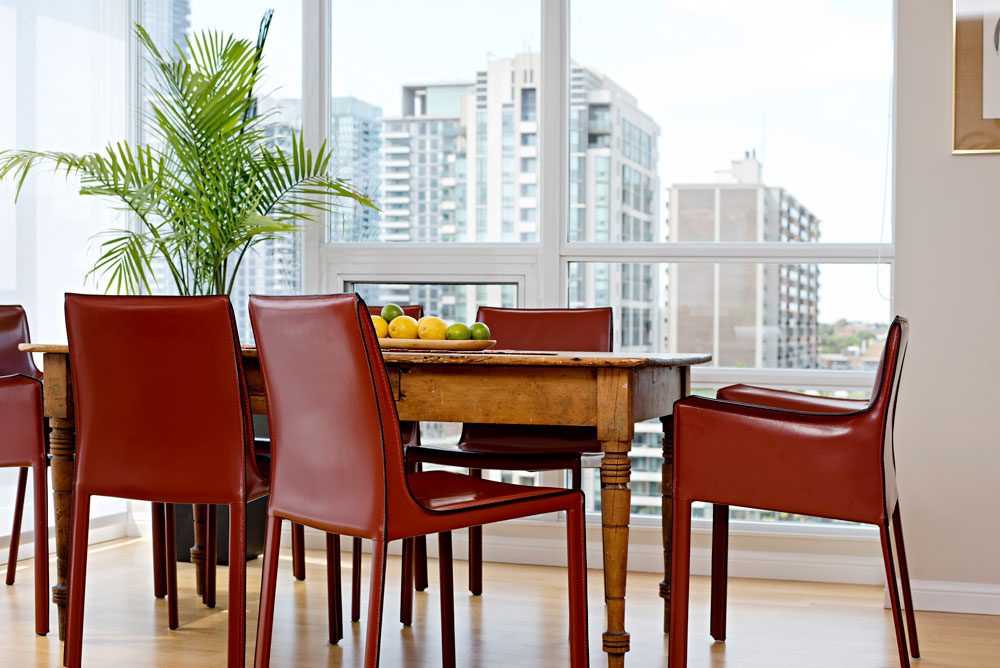 rustic dining table with modern red/brown leather chairs, with nice exterior view - fine finishes design inc