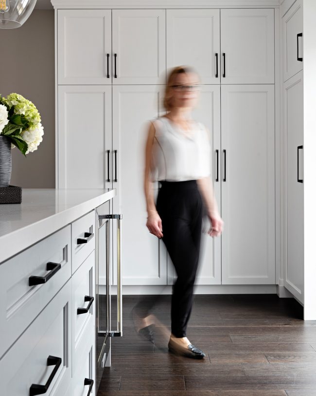 designer walking by kitchen island, 2 step shaker panel in white